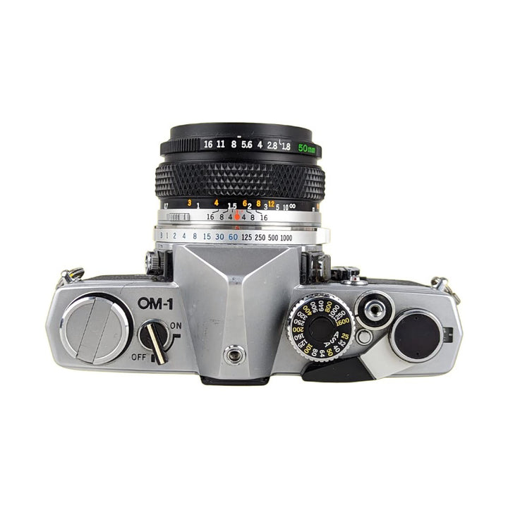 Olympus OM-1 SLR with 50mm f/1.8 lens showing shutter speed dial and exposure meter at ClubCamera.com