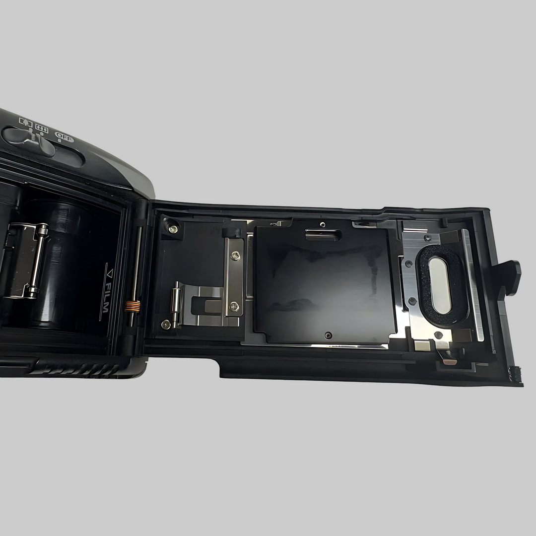 Open film compartment of black Canon 35mm camera revealing internal spool holder and pressure plate at ClubCamera.com