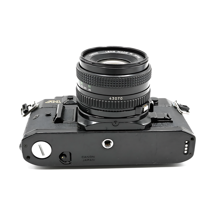 Bottom view of black Canon A-1 SLR showing tripod socket and Japan engraving with FD 50mm lens at ClubCamera.com