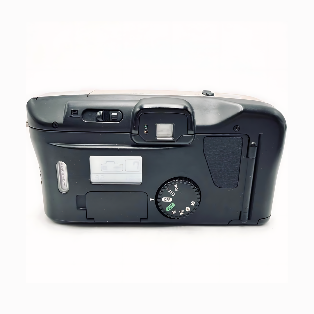 Bottom view of black Canon Prima Super 135 showing textured grip, mode dial icons, LCD status window, and serial number sticker at ClubCamera.com