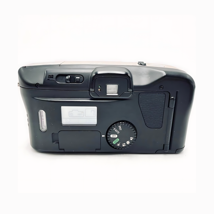 Bottom view of black Canon Prima Super 135 showing textured grip, mode dial icons, LCD status window, and serial number sticker at ClubCamera.com