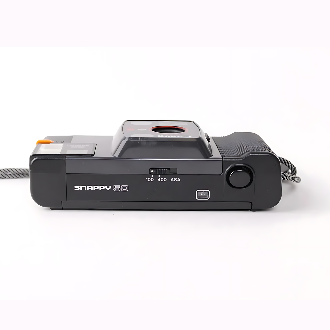 Bottom view of Canon Snappy 50 displaying sliding ASA selector and shutter release button at ClubCamera.com