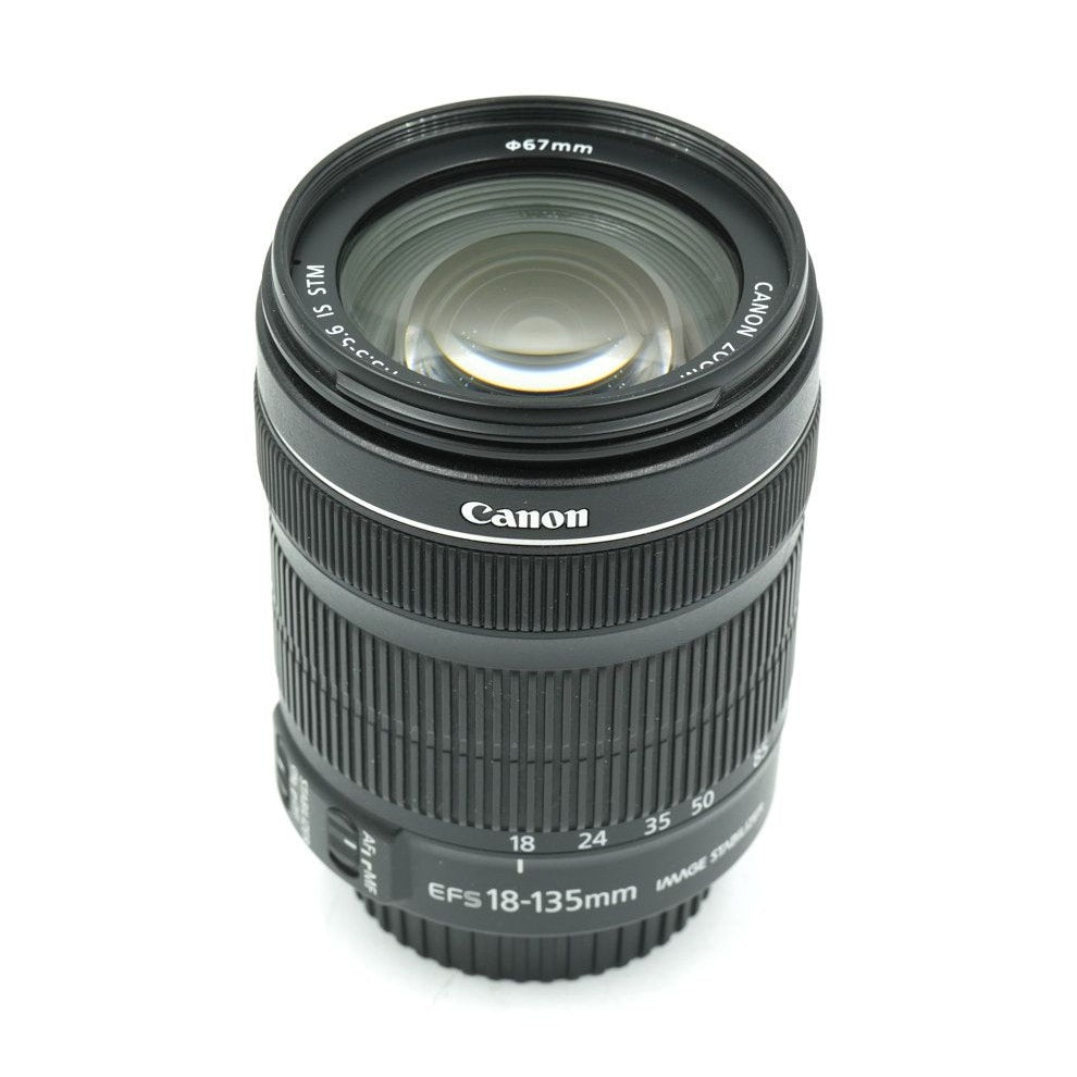 ClubCamera black Canon EF-S 18-135mm side profile showing ribbed grip rings and golden lens coating reflection