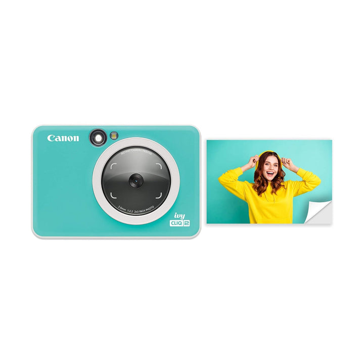 Canon Ivy Cliq2 Turquoise instant camera with matte finish and white lens ring next to peel-and-stick photo at ClubCamera.com