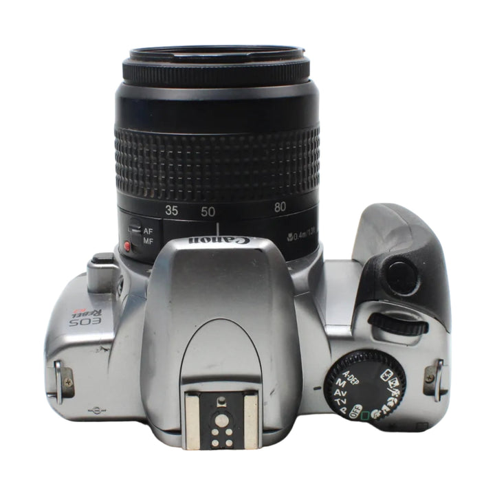 ClubCamera.com top-down Canon EOS Rebel K2 showing mode dial, AF/MF switch, and pop-up flash on silver body