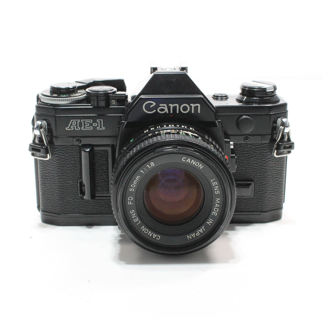 Canon AE-1 Black 35mm SLR Film Camera by ClubCamera.com with FD 50mm lens, matte black metal body and textured grip