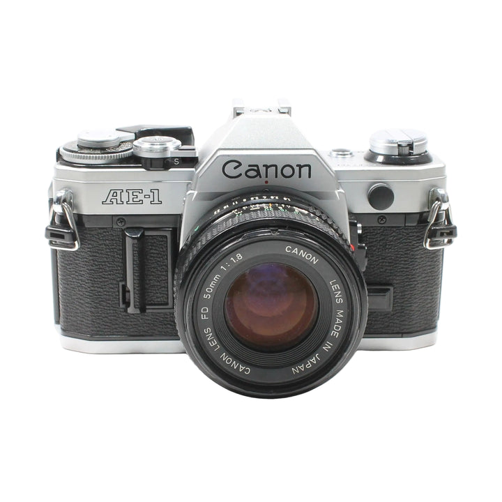 Canon AE-1 35mm SLR film camera with FD 50mm lens at ClubCamera.com showing black leatherette body and silver top plate