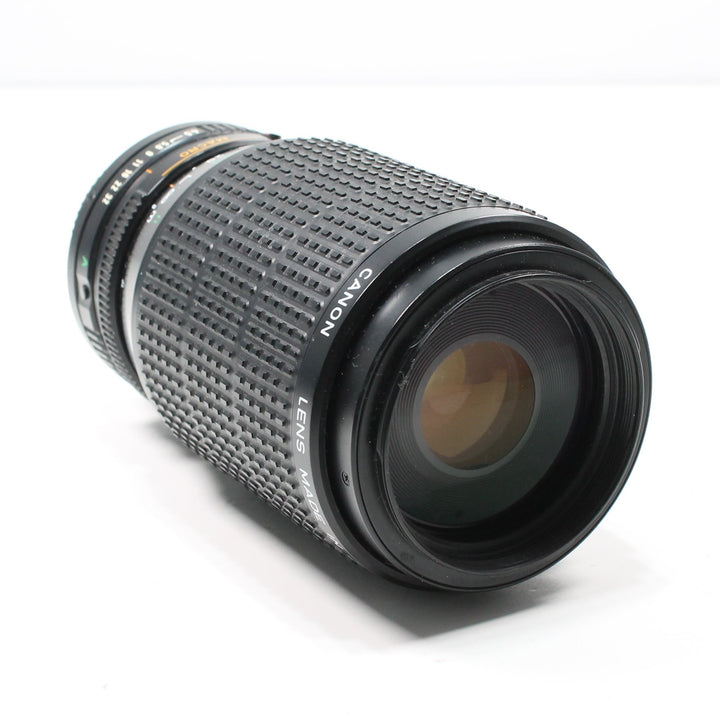 ClubCamera.com Canon FD 75-200mm telephoto zoom lens with white logo and amber multi-coated glass reflections