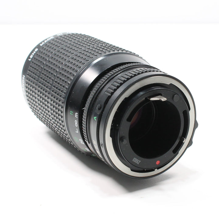 Rear view of Canon FD mount lens at ClubCamera.com featuring silver bayonet ring, red alignment dot, and distance scale