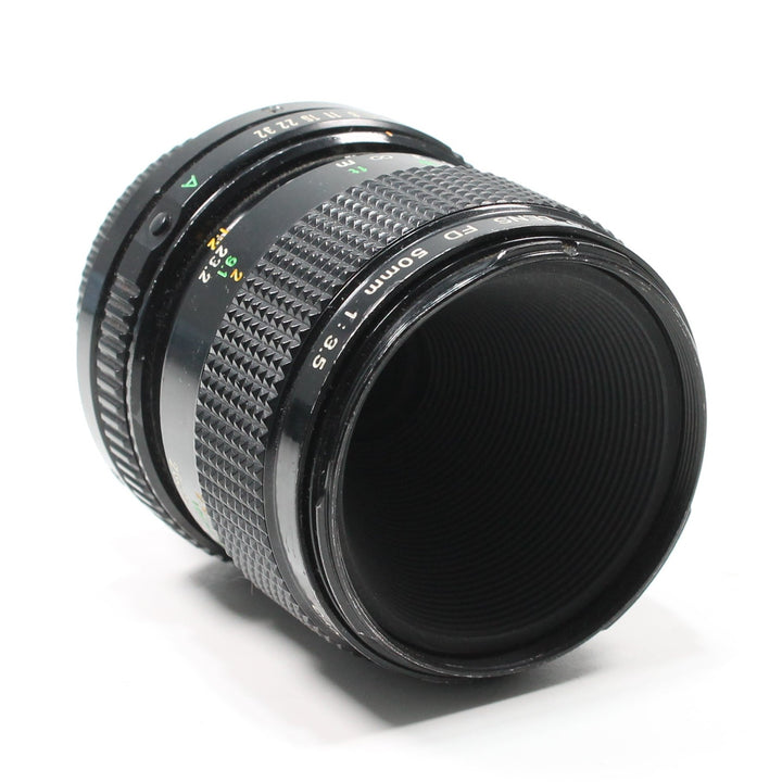 Side-rear angle of Canon FD 50mm f/3.5 Macro manual lens showing aperture scale and glass element at ClubCamera.com