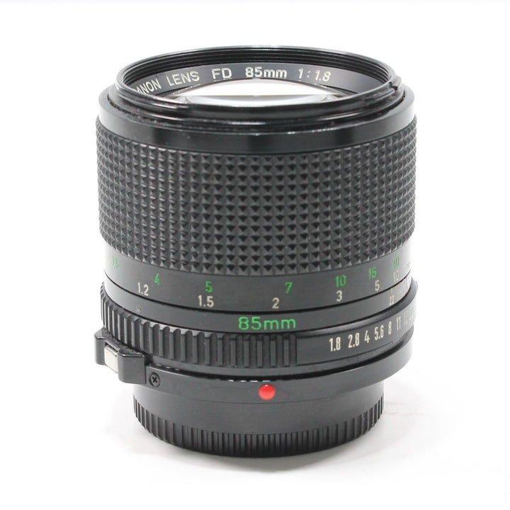 Close-up of black Canon FD 85mm f/1.8 prime lens with green engraved markings and red alignment dot from ClubCamera.com