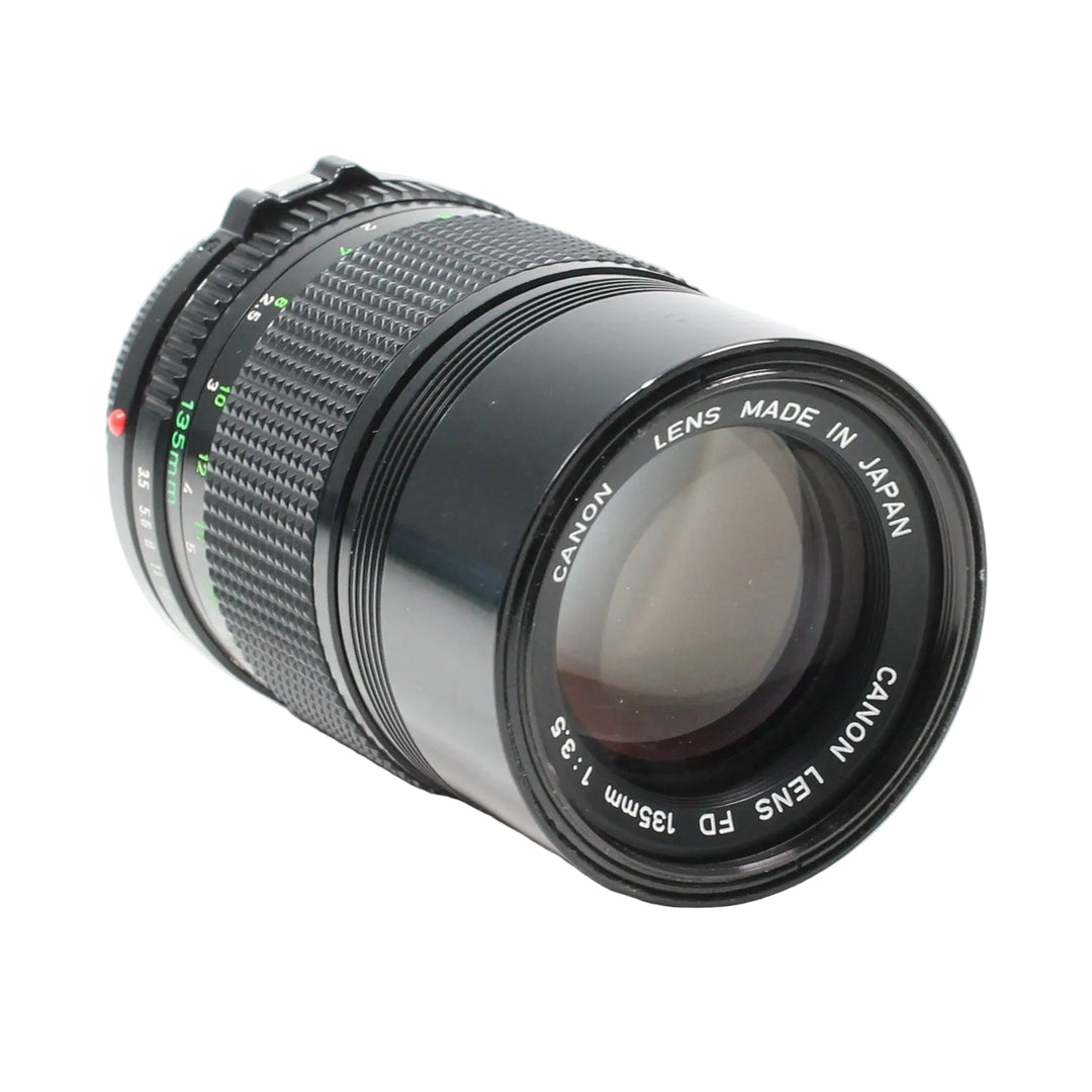 ClubCamera.com Canon FD 135mm f/3.5 vintage prime lens three-quarter view displaying CANON LENS FD 135mm 1:3.5 rim text and red alignment dot