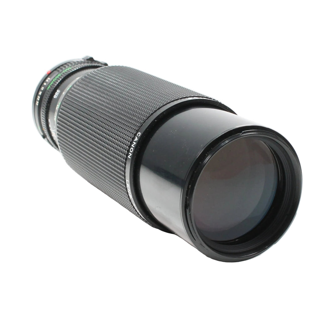 Diagonal view of black Canon FD 100-300mm f/5.6 vintage telephoto zoom lens at ClubCamera.com