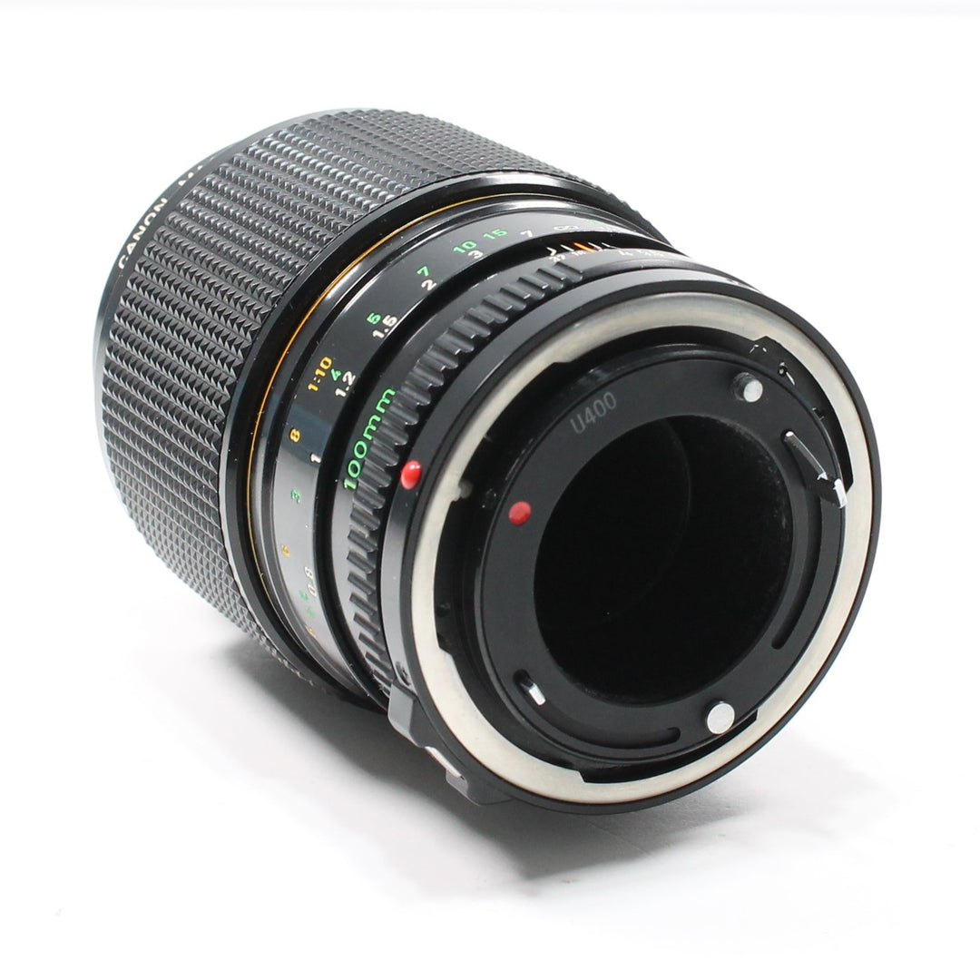 Rear angle of Canon FD 100mm f/4 macro lens at ClubCamera.com revealing silver bayonet mount interface