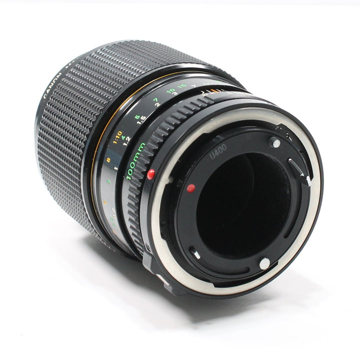 Rear angle of Canon FD 100mm f/4 macro lens at ClubCamera.com revealing silver bayonet mount interface