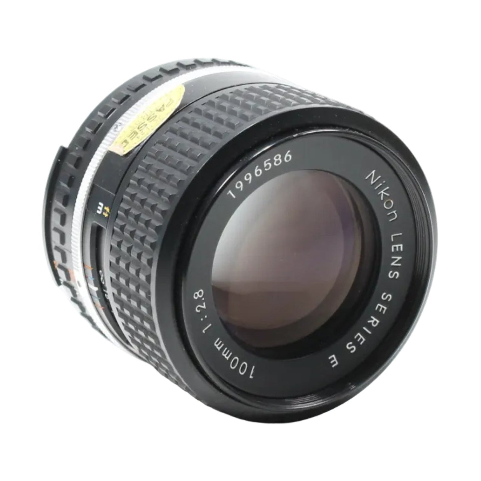 Diagonal view of vintage black Nikon 100mm f/2.8 prime lens with yellow sticker and purple reflection at ClubCamera.com