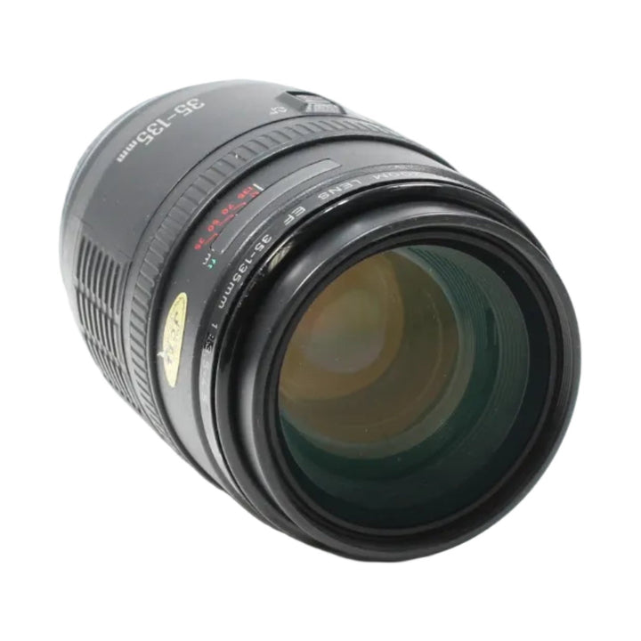 Black Canon zoom lens side angle showing green amber glass reflections and textured grip rings