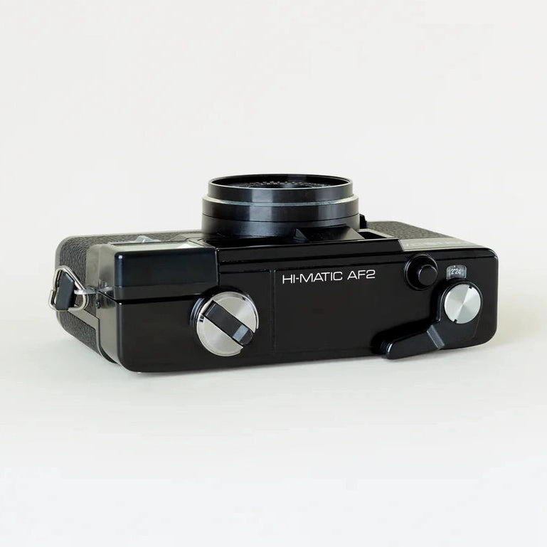 Black Minolta Hi-Matic AF2 film camera top rear view with textured grip and silver advance knob at ClubCamera.com