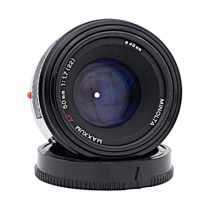 Front of black Minolta AF 50mm F1.7 lens showing blue-purple coating and MAXXUM branding at ClubCamera.com