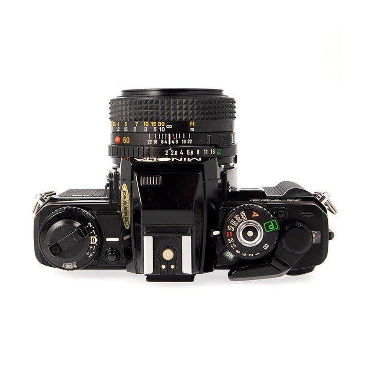 ClubCamera.com top-down view of black Minolta X-700 SLR highlighting mode dial, shutter speed selector, and focus scale