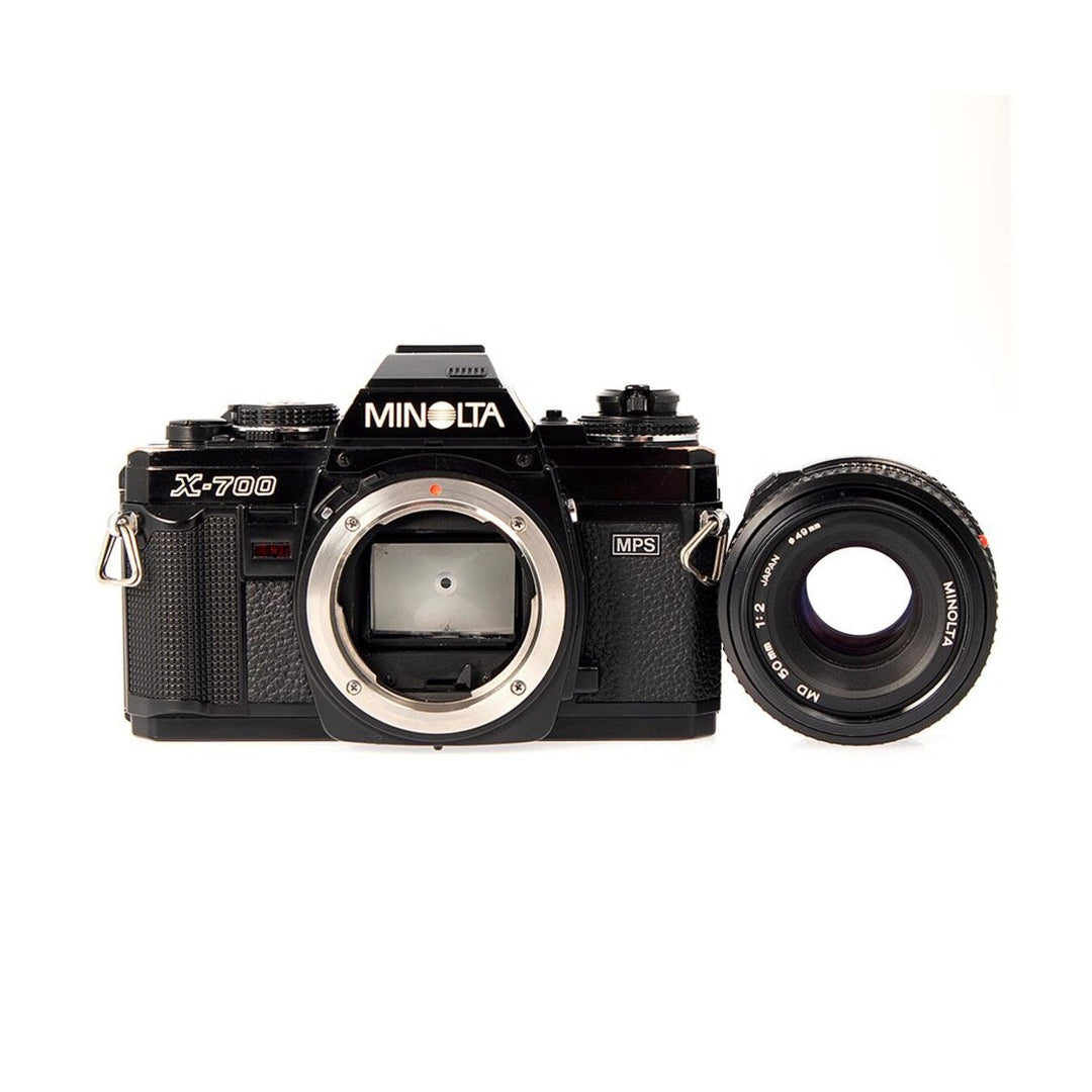 ClubCamera.com black Minolta X-700 SLR body with detached MD 50mm f/2 lens showing engraved markings and sensor mount