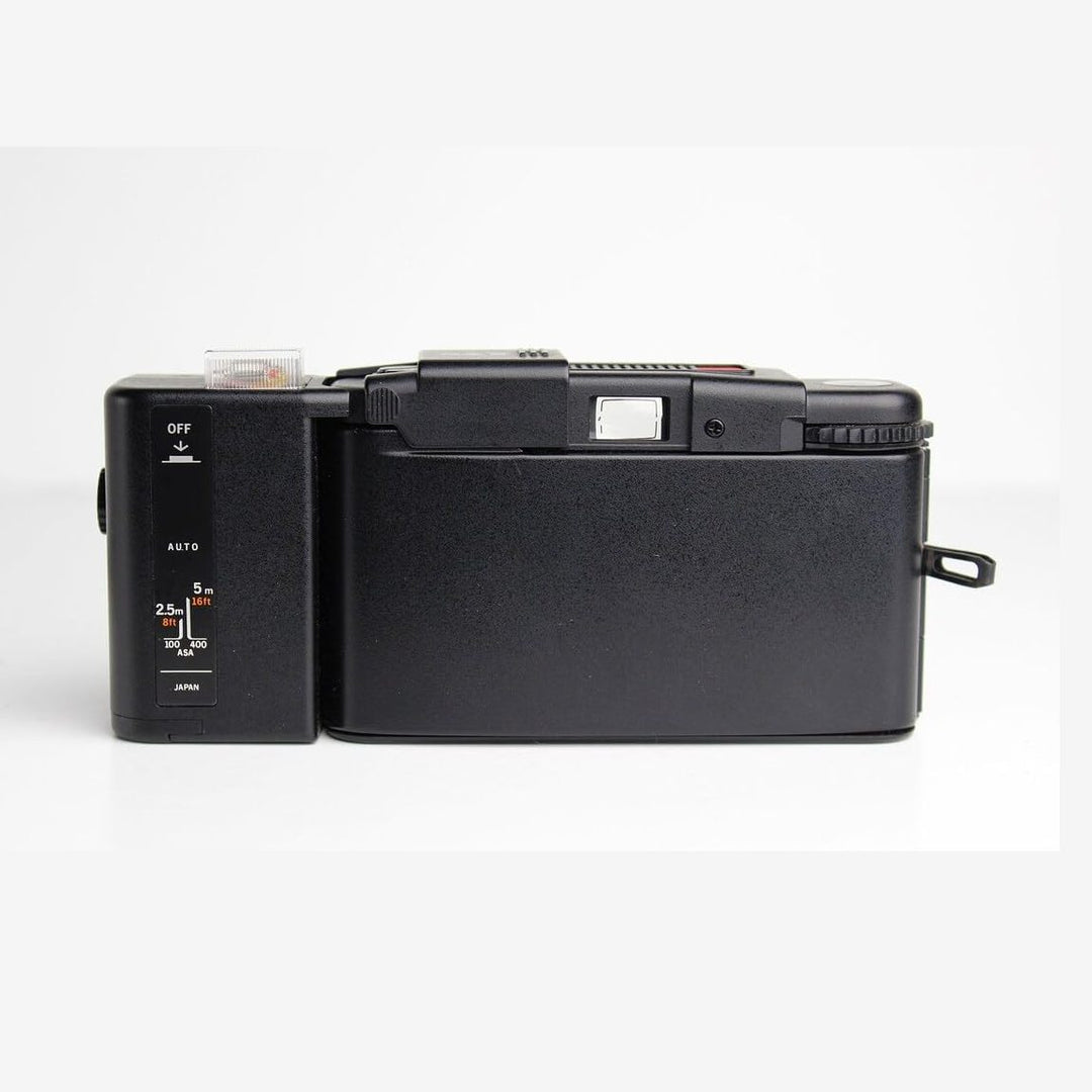 Slim black Olympus XA side profile showing ASA settings and strap loop at ClubCamera.com