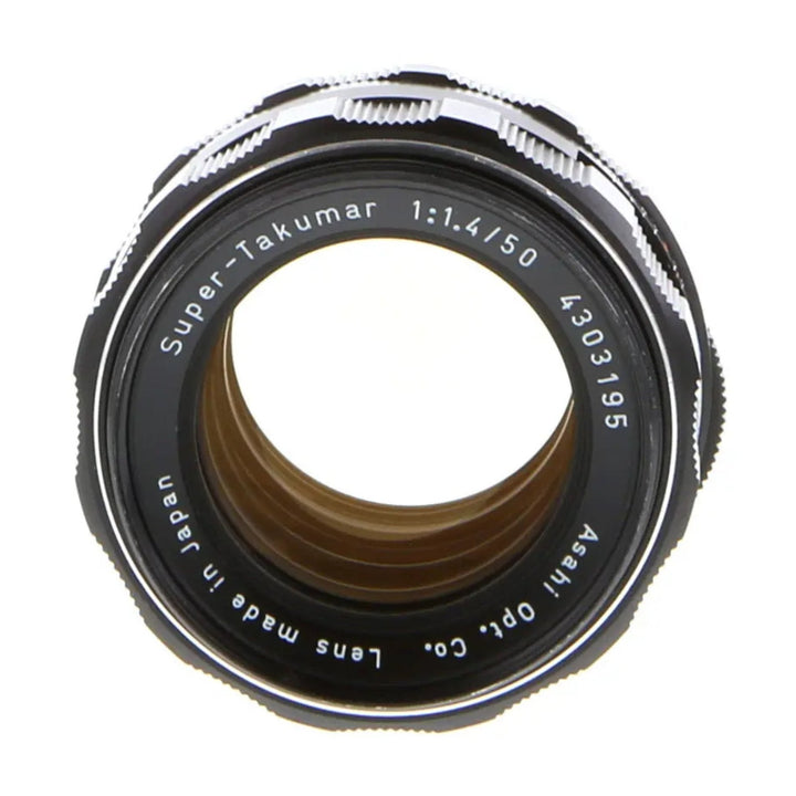 Top-down view of Pentax Super-Takumar 50mm f/1.4 lens revealing internal brown-tinted elements and serial number at ClubCamera.com