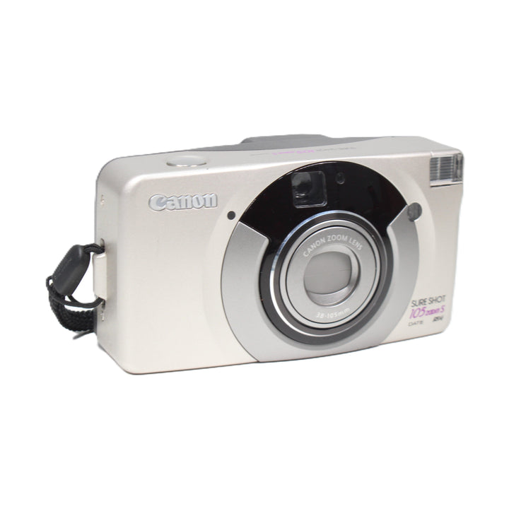 ClubCamera angled front shot of silver Canon Sure Shot 105 Zoom S with black wrist strap attached