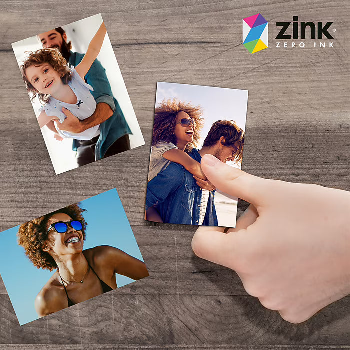 ClubCamera.com glossy ZINK instant photo prints on wood surface demonstrating vibrant colors and smooth finish held by hand