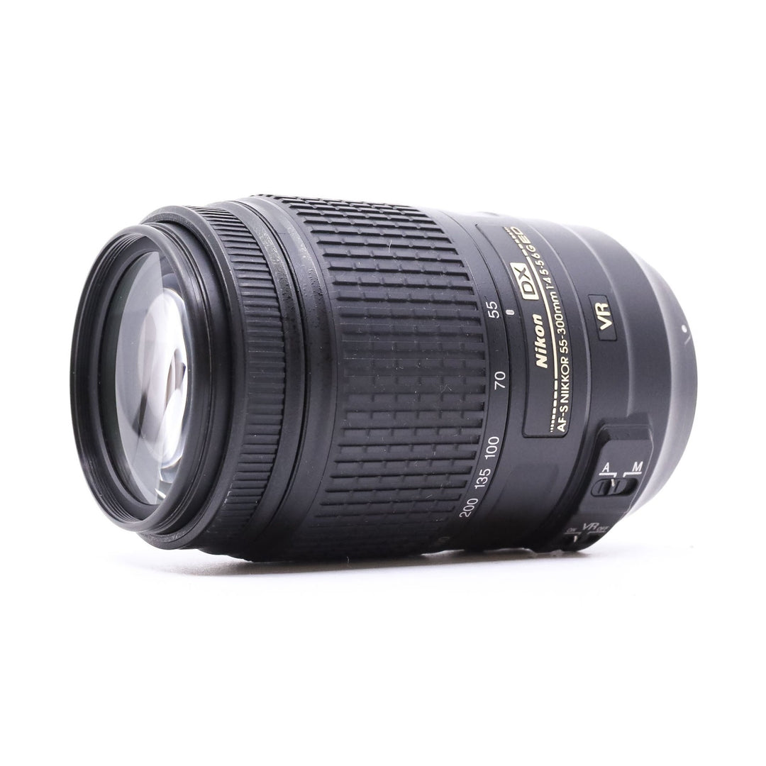 Three-quarter angle of Nikon AF-S 55-300mm ED VR lens highlighting multi-coated glass element and ergonomic grip from ClubCamera