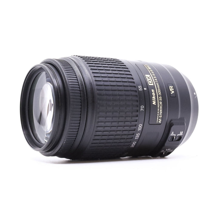 Three-quarter angle of Nikon AF-S 55-300mm ED VR lens highlighting multi-coated glass element and ergonomic grip from ClubCamera