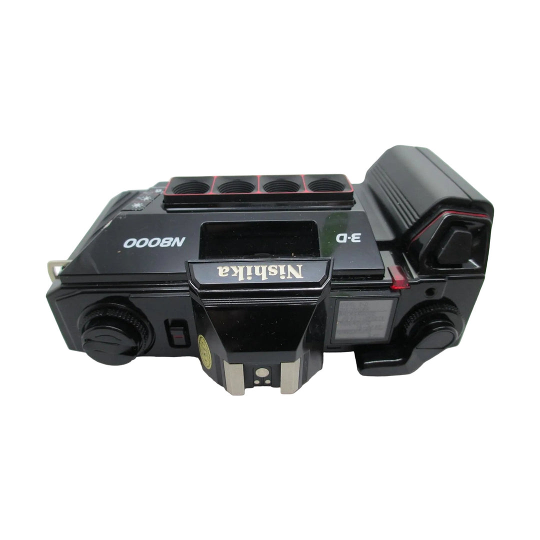 Top angled view of black Nishika N8000 3D point-and-shoot camera showing hot shoe and textured dials at ClubCamera.com