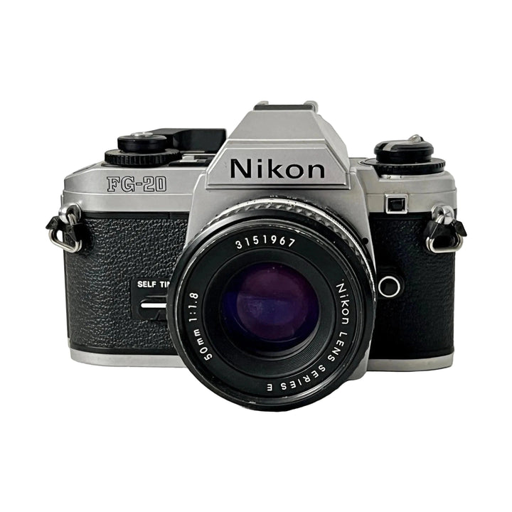 Front shot of silver Nikon FG-20 35mm film SLR with 50mm f/1.8 Series E lens, black lettering and self-timer button available at ClubCamera.com
