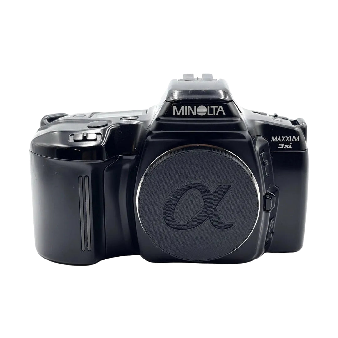 Front view of black Minolta Maxxum 3xi 35mm SLR with retracted flash and alpha logo lens cap from ClubCamera.com