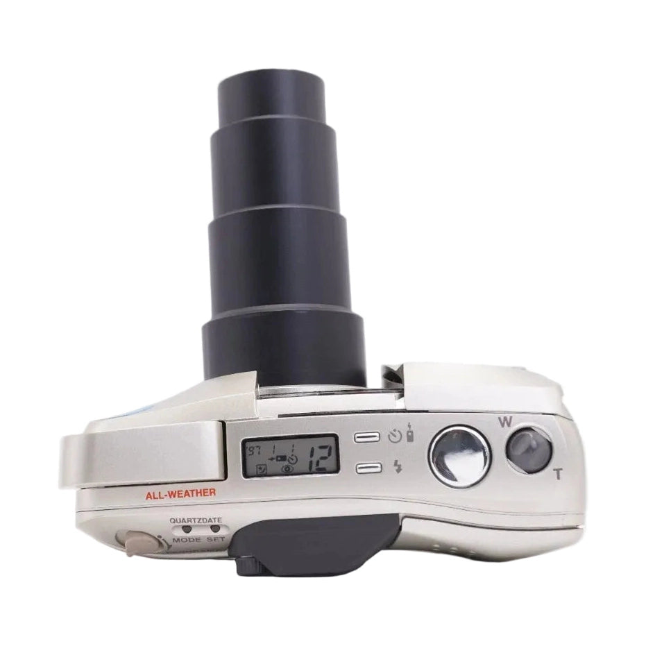 ClubCamera silver Olympus Stylus Epic Zoom 140 top view showing extended zoom lens, LCD screen, and all-weather label