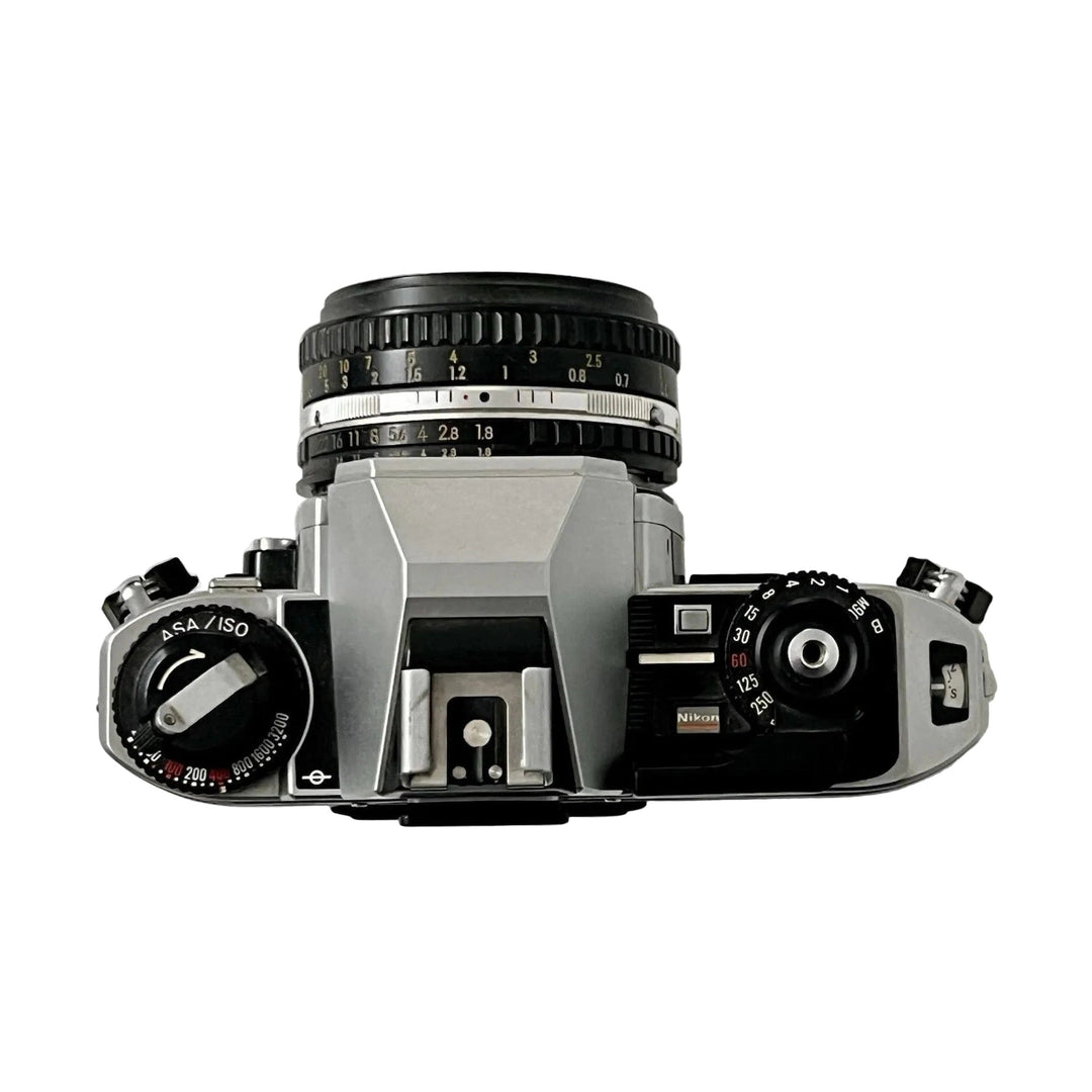 Top-down view of silver and black Nikon FG-20 35mm film SLR camera with 50mm lens, ASA/ISO and shutter speed dials at ClubCamera.com