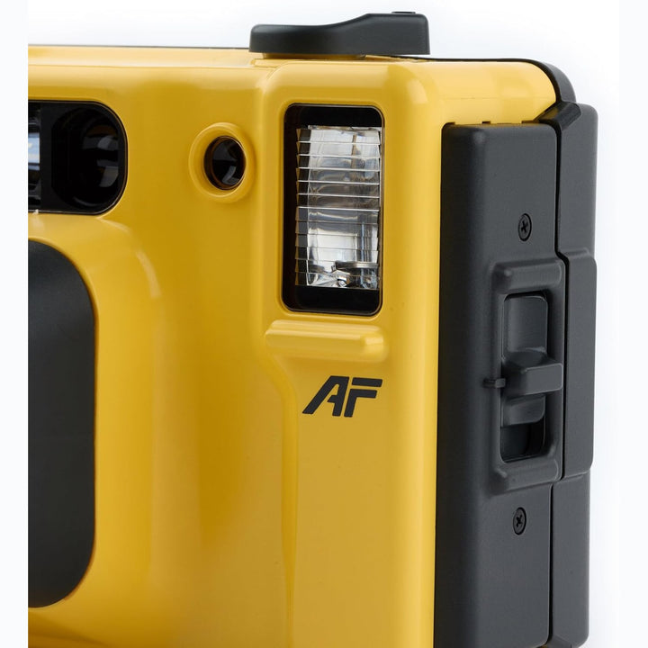 Side profile of Minolta Weathermatic built-in flash with AF logo and black latch on yellow body at ClubCamera.com